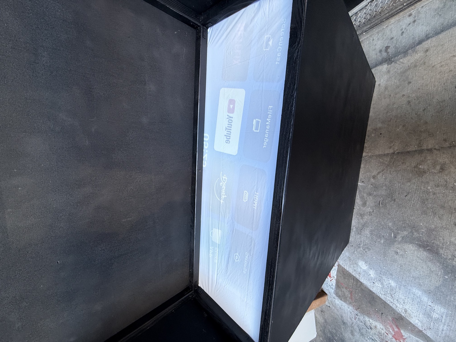 A tablet's home screen reflected in the angled acrylic inside the finished display box
